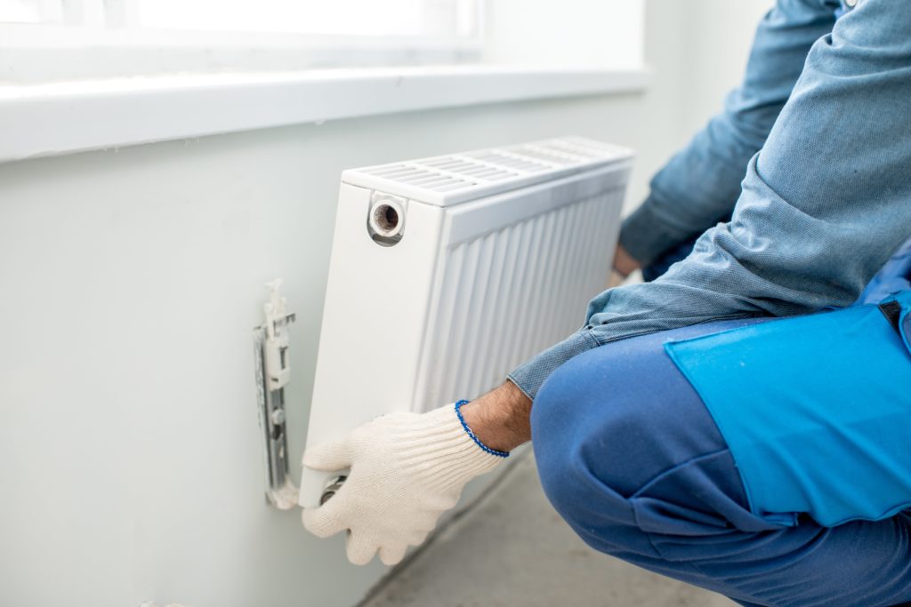 Ein Sanitär von Reci Haustechnik baut eine Heizung ein